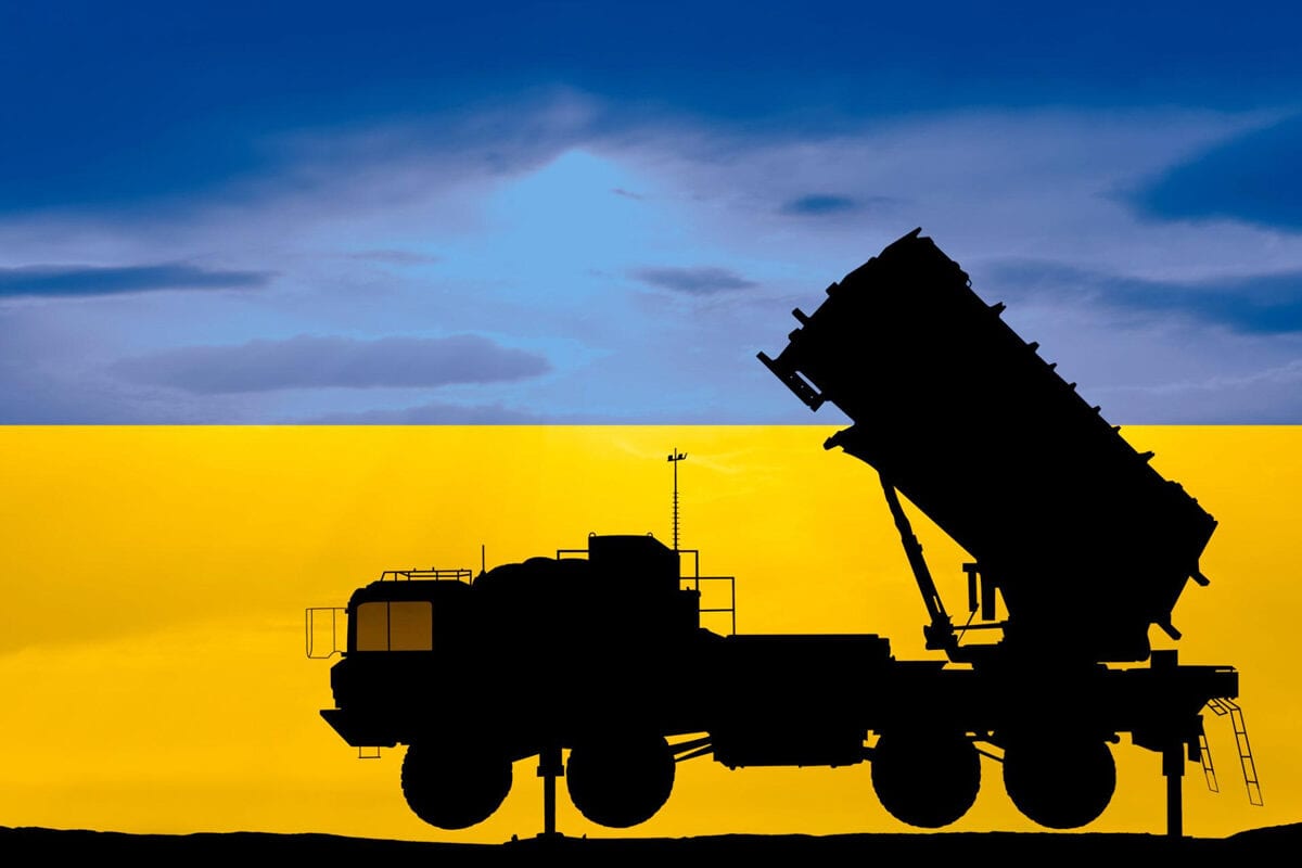 Priešlėktuvinės raketų sistemos paleidimo įrenginio siluetas mėlynos ir geltonos Ukrainos vėliavos fone