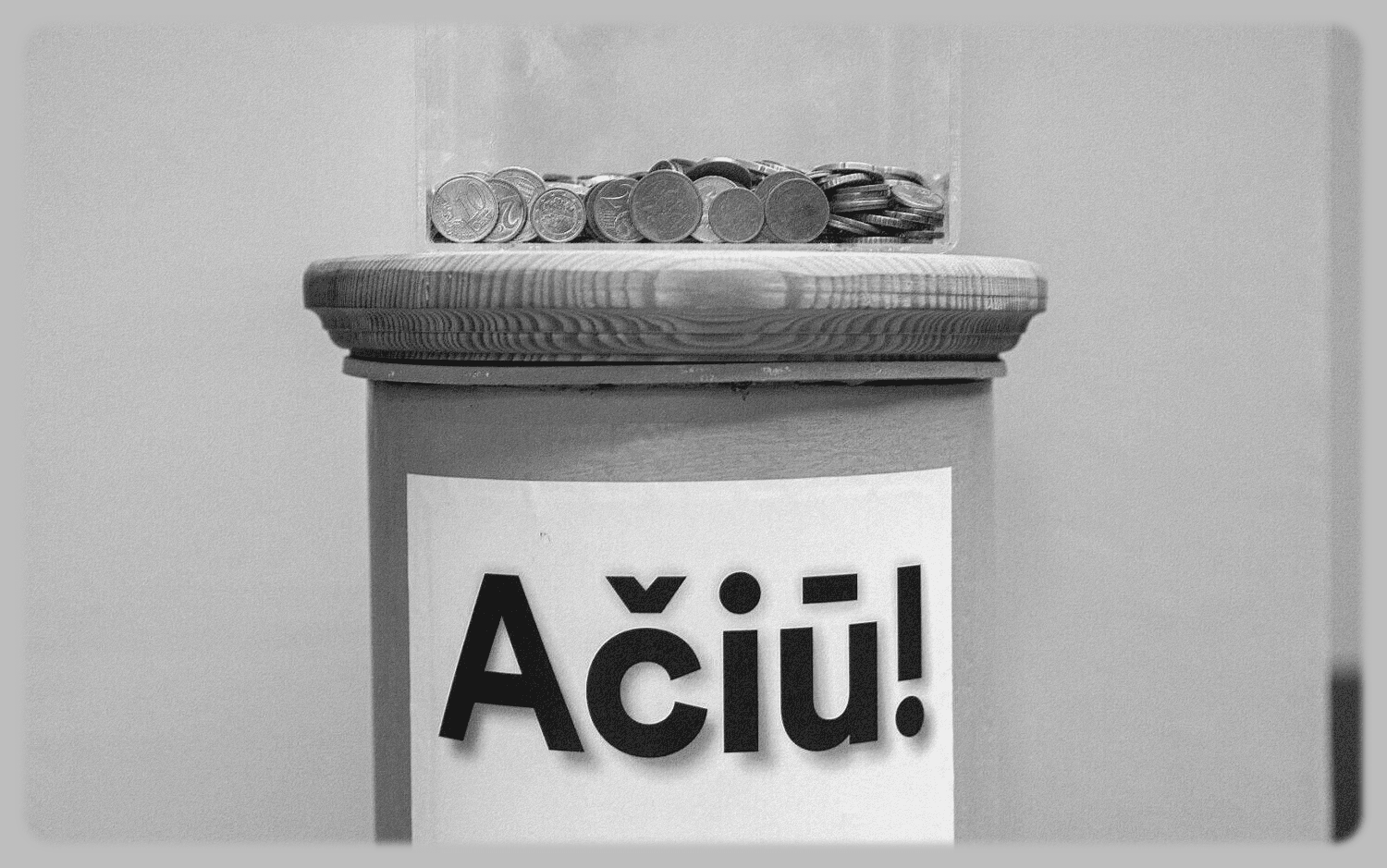 Nespalvota aukų dėžutė su monetomis ant medinio dangčio ir užrašu Ačiū